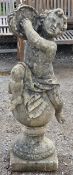 Weathered reconstituted stone garden statue of a musical cherub seated on a ball pier cap playing