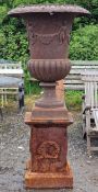 Large cast iron Campana urn with lobed bowl and winged cherub relief, raised on a square cut
