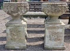 Haddonstone - Pair of reconstituted stone garden urns with ornate foliate swag relief, raised on