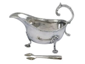 A white metal sauce boat - with a bead pattern rim, leaf C-scroll handle and raised on three shell
