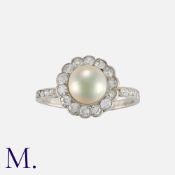 A Pearl and Diamond Cluster Ring in platinum, set with a round cream pearl (dia 7mm) with round