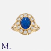 A Sapphire and Diamond Cluster Ring in 18 carat yellow gold, comprising a cabochon sapphire of