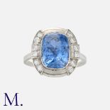 A French Art Deco Sapphire and Diamond Cluster Ring in platinum, set with a cushion cut sapphire