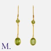 A Pair of Peridot Drop Earrings in yellow gold, each comprising a round cut peridot, suspending a