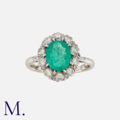 An Emerald and Diamond Cluster Ring in white gold, set with an oval cut emerald of approximately 1.