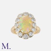 An Opal and Diamond Cluster Ring in 18K yellow gold, set with an oval cabochon opal (with red,