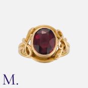 A Garnet Snake Ring in yellow gold, set with an oval cut garnet accented by two coiled snake motifs.