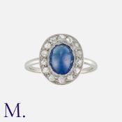 A Cabochon Sapphire and Diamond Ring in platinum, set with a cabochon sapphire to the centre with
