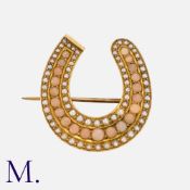 An Antique Coral and Pearl Horseshoe Brooch in yellow gold, set with a row of cabochon coral with
