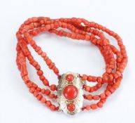 A four-strand blood coral bracelet with a 14kt yellow gold clasp and gold safety chain, hallmarked '