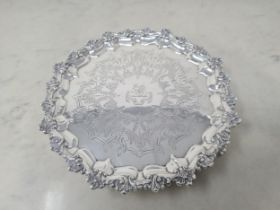 A Victorian silver circular salver with scallop border, scroll engraved with crest and motto on