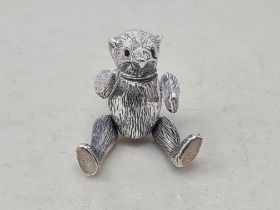 A silver miniature Pin Cushion in the form of an articulated teddy bear with faceted red glass eyes