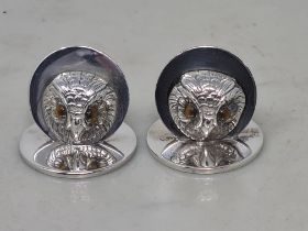 A pair of George V silver Menu Holders in the form of owl masks on circular bases, London 1919,