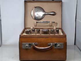 A George V leather Dressing Case containing nine silver mounted fittings with hammered design,