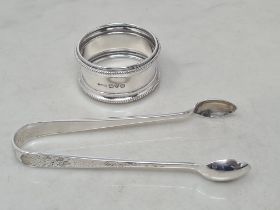 A George V silver circular Napkin Ring, Chester 1917, and a pair of Sugar Tongs, Sheffield 1902