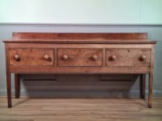 An oak Dresser Base with slightly raised back fitted with three drawers raised on tall square