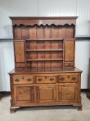 An antique oak Dresser and Rack, the rack with shaped frieze and fitted two cupboard doors, the base