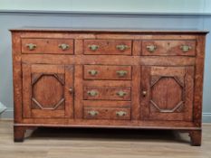 A Georgian oak Dresser Base fitted three drawers above pair of doors flanking further drawer and two