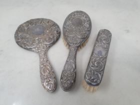 A silver mounted three piece Dressing Table Set with bird and floral scroll embossing, Birmingham