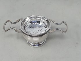 An Elizabeth II silver two handled Tea Strainer and Stand, London 1976/7, 120gms