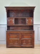 An 18th Century oak Canopy Dresser, the rack fitted pair of fielded panel doors above enclosed