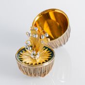 A DECORATIVE SILVER EGG WITH FLOWER BROOCH