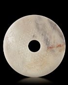A CHINESE BI DISC DECORATED WITH A BORDER OF FOUR ANIMAL HEADS INTERTWINED TO FORM A PATTERN, LATE E