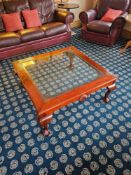 Square coffee table with inset glass top framed by richly carved wood, featuring shell motifs and