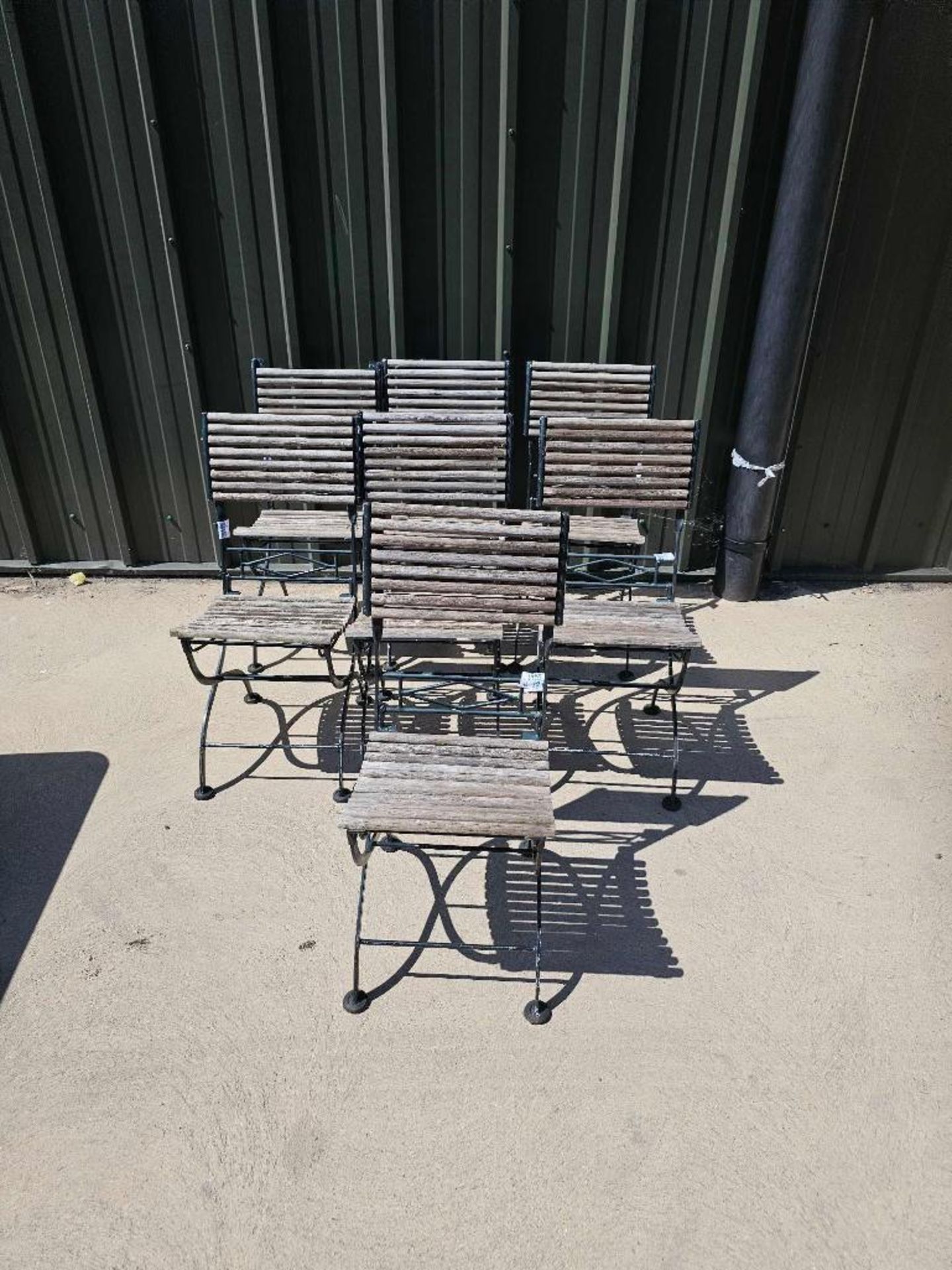 A set of seven vintage French folding bistro chairs features a weathered, rustic aesthetic