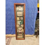 A tall, vertical shadow box serves as a curated display of vintage memorabilia and advertisements