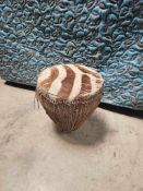 A zebra skin floor drum featuring a tapered, conical body wrapped in tightly woven natural fibre