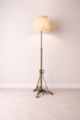 Antique Brass Floor Lamp An antique brass floor lamp with a slender tripod base, featuring intricate