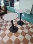 A pair bistro-style pedestal tables feature a durable and stylish circular stone-effect top,
