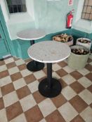 A pair bistro-style pedestal tables feature a durable and stylish circular stone-effect top,