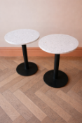 A pair bistro-style pedestal tables feature a durable and stylish circular stone-effect top,