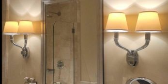 A matching pair of wall‑mounted twin‑arm light fixtures in polished nickel, each formed in a