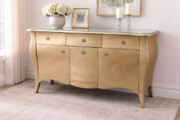 A three-drawer, three-door sideboard featuring an elegant, serpentine front and a glamorous metallic