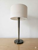 Numirra table lamp in an antique brass finish, featuring a slender, tapered spindle stem set upon