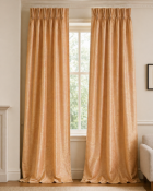 A pair of full-length curtains in a soft peach-coloured textured fabric, featuring a pleated