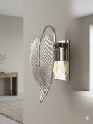 A wall-mounted sconce featuring a decorative curved metal shade in the form of a ribbed leaf with