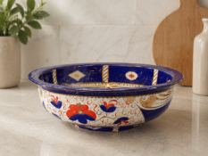 A large ceramic fruit bowl featuring a traditional Imari-inspired palette of cobalt blue, iron