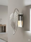 Wall-mounted sconce with curved ribbed leaf-shaped metal shade in polished silver finish. Matching