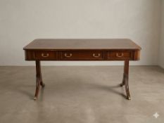 A mahogany sofa-style writing desk of Regency design. The expansive rectangular top features an