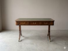 A mahogany sofa-style writing desk of Regency design. The rectangular top features an inset green