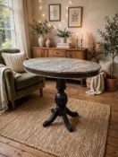 A striking high-poser bar table featuring a thick oval marble top panel over a single black wooden