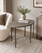 An ovoid-form coffee table featuring a bronzed metal frame with four tapered legs. The structure