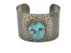 VINTAGE STERLING SILVER HAMMERED CUFF BRACELET FEATURING AN OVAL SHAPED TURQUOISE IN CENTER