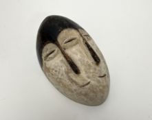 A Ngbaka mask of oval form with two semi-circular open mouths, two triangular noses and three