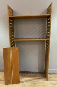 A mid-century teak wall-mounted shelving unit, ladder-style sides united by three adjustable