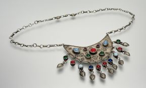 An Iranian white metal crescent shaped pendant with inset coloured glass beads and matching bead and